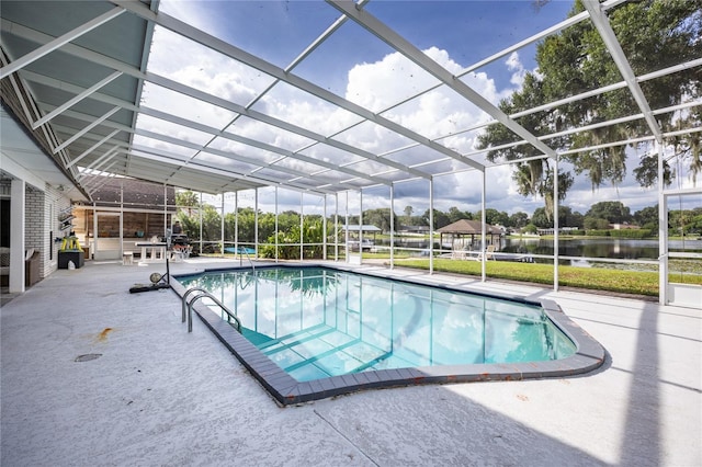 pool with a patio area, glass enclosure, and a water view