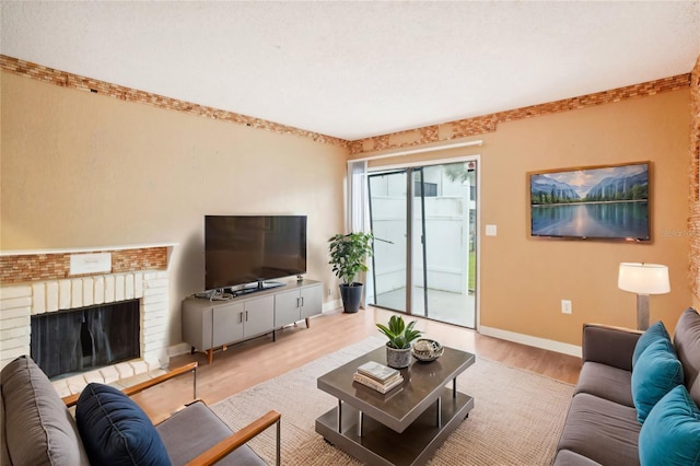 living room with light wood finished floors, a brick fireplace, and baseboards