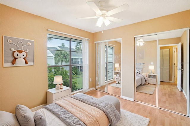 bedroom featuring light wood-style floors, ceiling fan, baseboards, and multiple closets