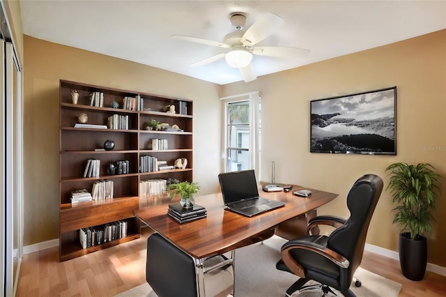 office featuring a ceiling fan, light wood-type flooring, and baseboards