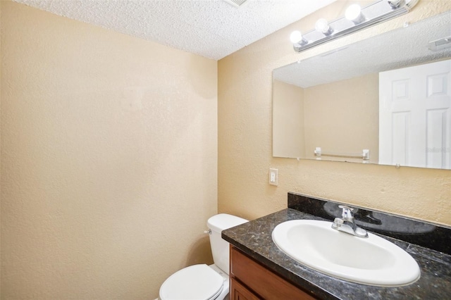 half bathroom with visible vents, a textured wall, toilet, vanity, and a textured ceiling