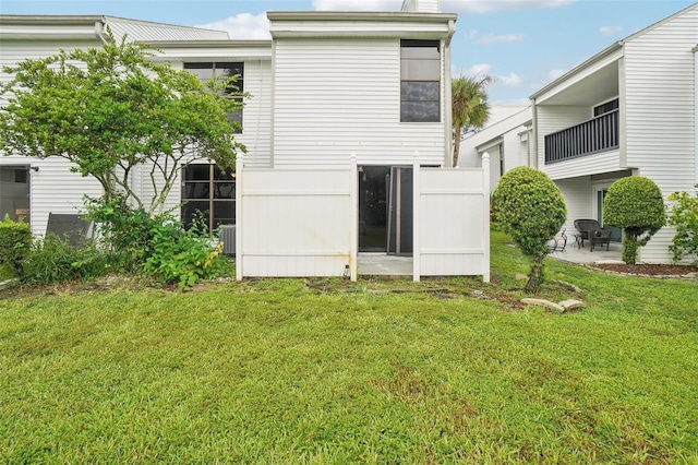 back of house with central AC and a lawn