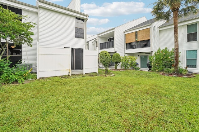 back of house with a balcony and a yard