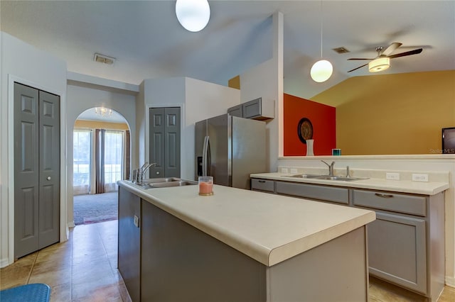 kitchen featuring stainless steel fridge, gray cabinetry, a kitchen island with sink, and sink