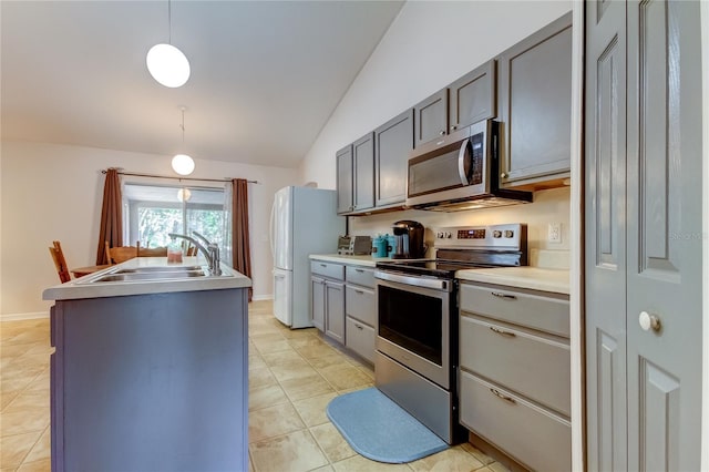 kitchen with vaulted ceiling, decorative light fixtures, light tile patterned floors, appliances with stainless steel finishes, and sink