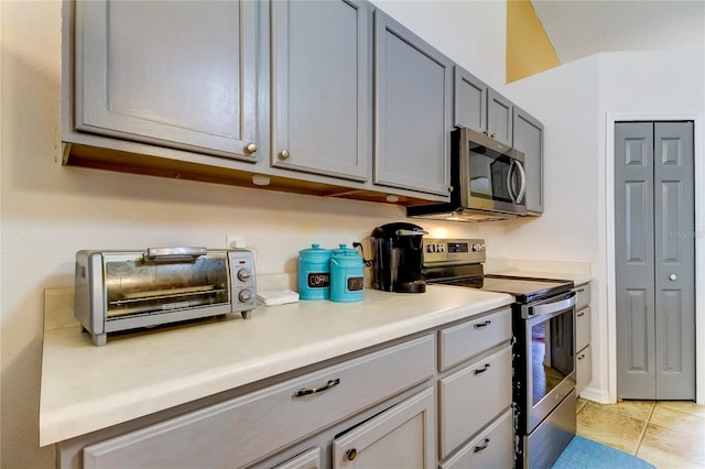 kitchen with gray cabinetry, appliances with stainless steel finishes, and light tile patterned flooring