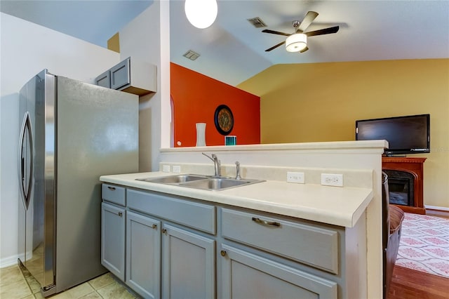 kitchen with stainless steel refrigerator, light tile patterned floors, sink, ceiling fan, and vaulted ceiling