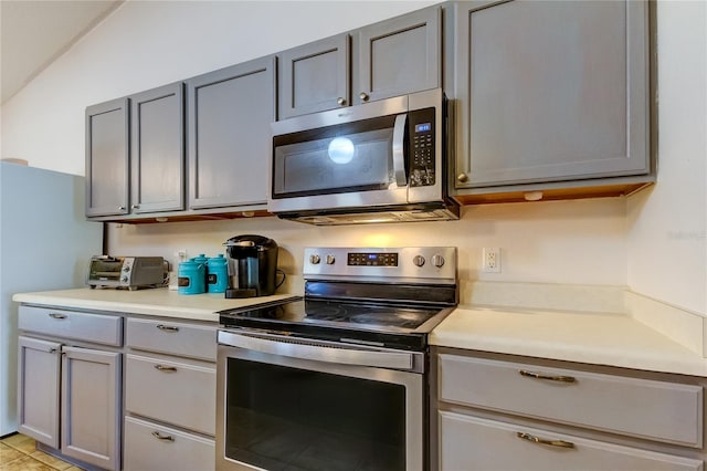 kitchen with light tile patterned floors, stainless steel appliances, and gray cabinets