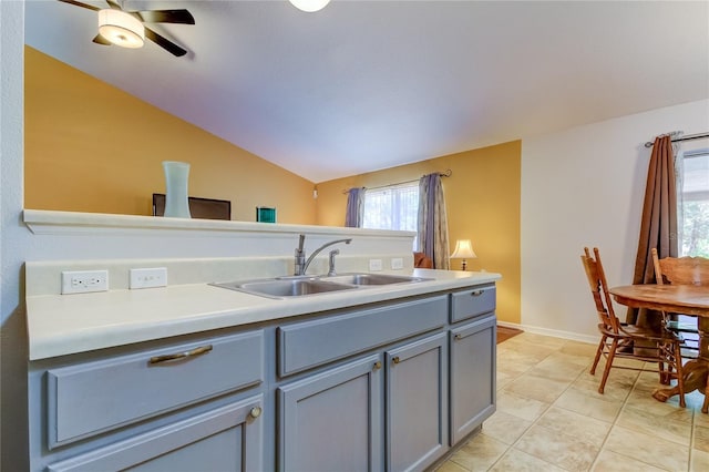 kitchen with gray cabinetry, light tile patterned floors, vaulted ceiling, sink, and ceiling fan