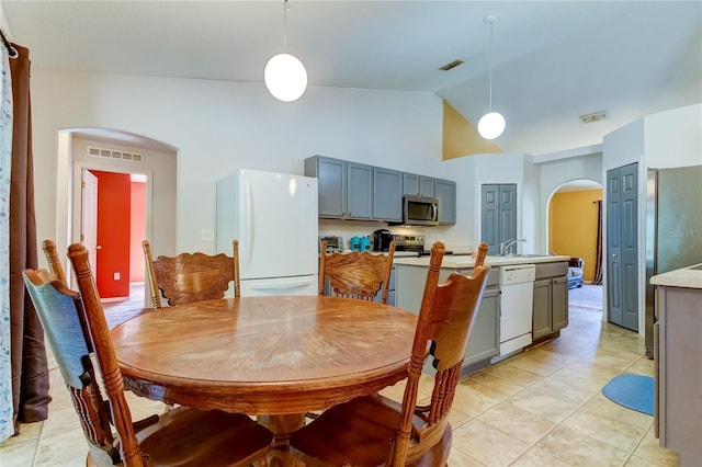 dining space with vaulted ceiling and light tile patterned flooring