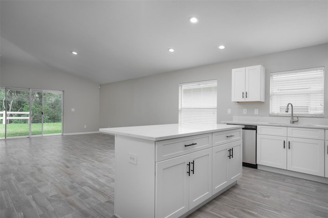 kitchen with white cabinets, dishwasher, a center island, light hardwood / wood-style floors, and sink