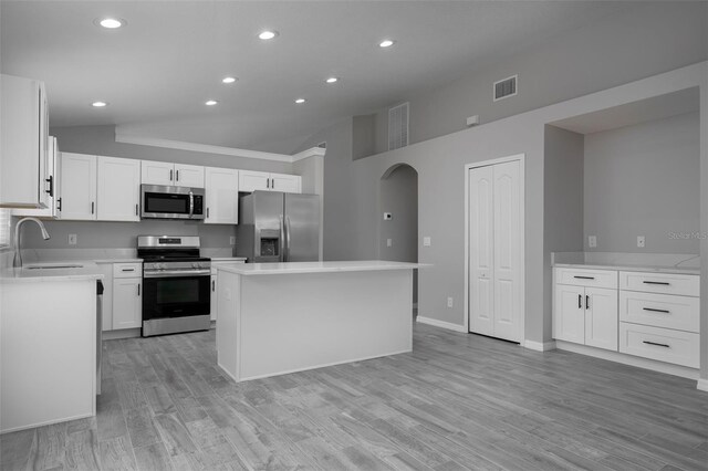 kitchen with white cabinets, light wood-type flooring, stainless steel appliances, sink, and a kitchen island