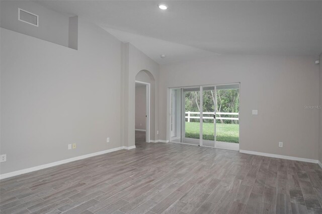 empty room with high vaulted ceiling and light hardwood / wood-style floors