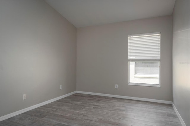 empty room featuring light wood-type flooring and vaulted ceiling