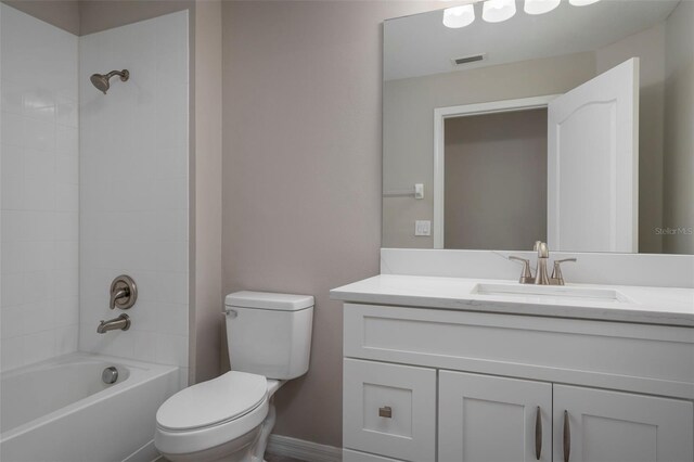 full bathroom featuring tiled shower / bath, vanity, and toilet