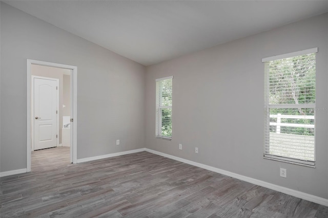 unfurnished room with lofted ceiling and light wood-type flooring