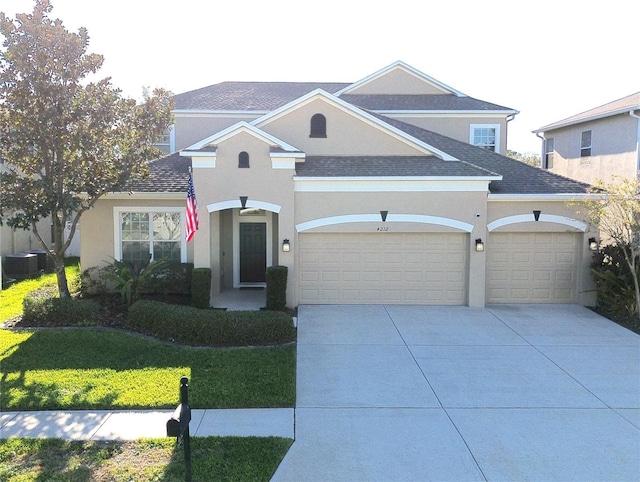 traditional-style home with concrete driveway, central AC, an attached garage, and stucco siding