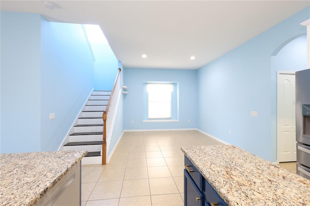 kitchen with light tile patterned floors, blue cabinets, and light stone counters