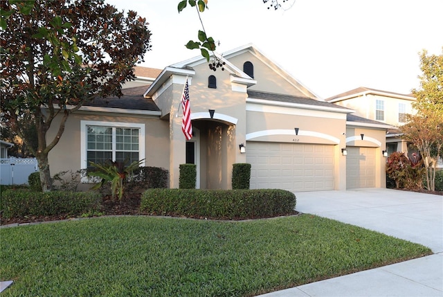 traditional-style house with driveway, an attached garage, a front lawn, and stucco siding