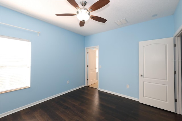 unfurnished bedroom featuring ceiling fan, dark wood-type flooring, and a textured ceiling