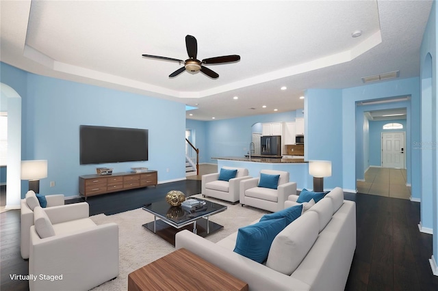 living room featuring a tray ceiling, ceiling fan, light hardwood / wood-style flooring, and sink