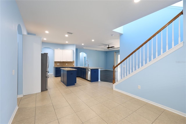 kitchen featuring white cabinets, blue cabinets, sink, a kitchen island, and a kitchen bar