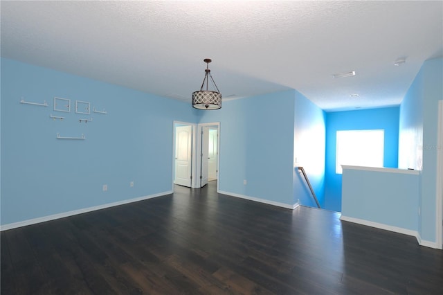 spare room featuring a textured ceiling and dark wood-type flooring