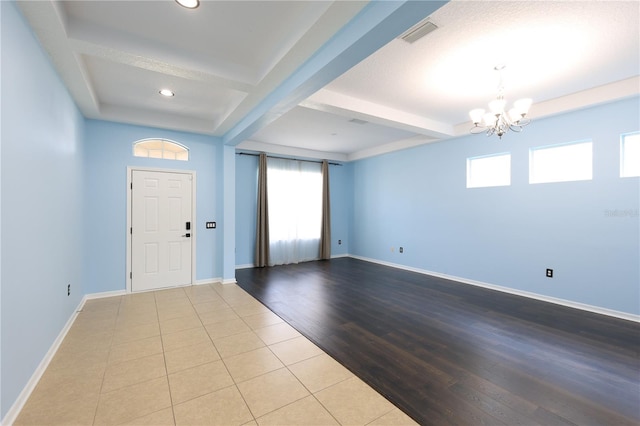 entrance foyer featuring beamed ceiling, plenty of natural light, light hardwood / wood-style floors, and a chandelier