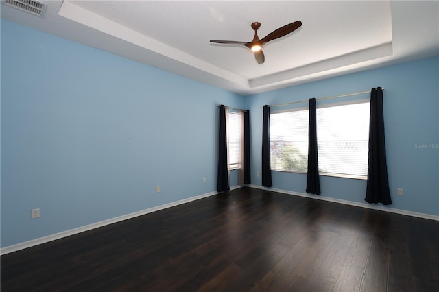 empty room featuring hardwood / wood-style floors, a raised ceiling, and ceiling fan