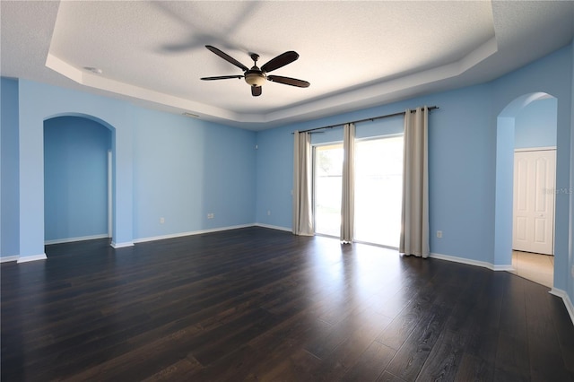 unfurnished room with dark hardwood / wood-style floors, ceiling fan, a raised ceiling, and a textured ceiling