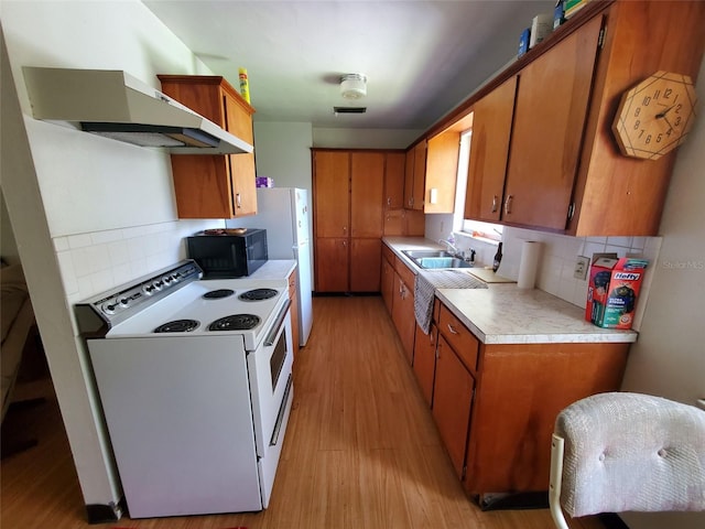 kitchen with tasteful backsplash, white electric range, wall chimney exhaust hood, sink, and light hardwood / wood-style floors