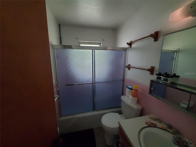 full bathroom with bath / shower combo with glass door, toilet, and vanity