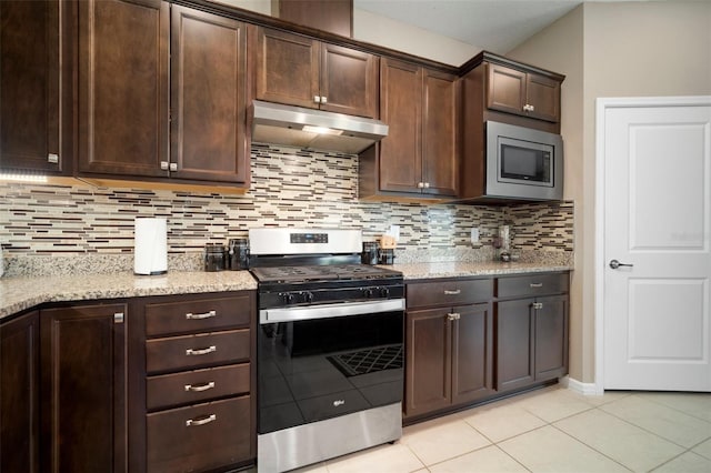 kitchen with backsplash, stainless steel appliances, dark brown cabinetry, light stone counters, and light tile patterned flooring