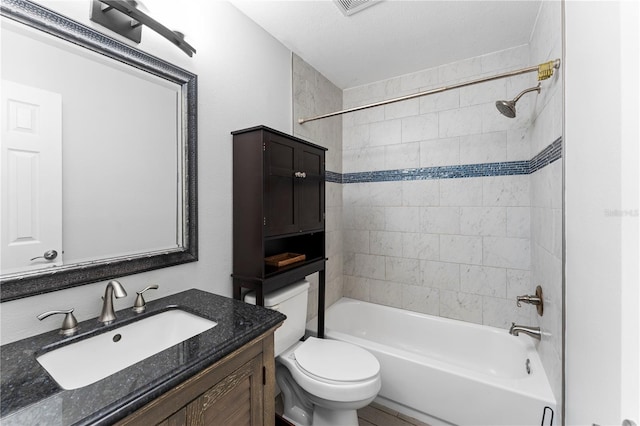 full bathroom featuring toilet, tiled shower / bath combo, vanity, and a textured ceiling