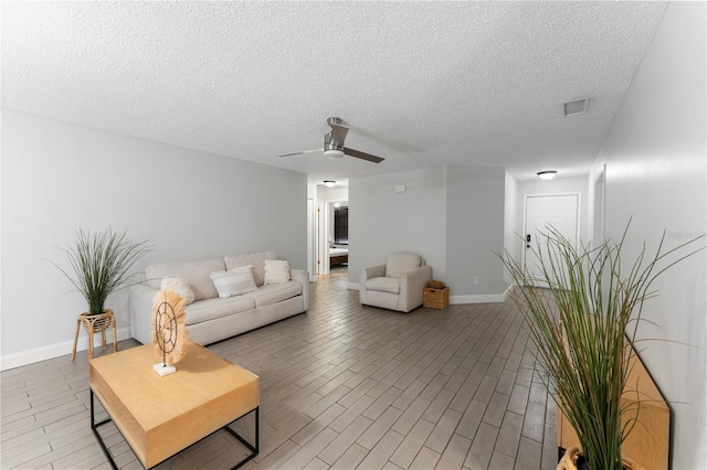 living room with a textured ceiling, wood-type flooring, and ceiling fan