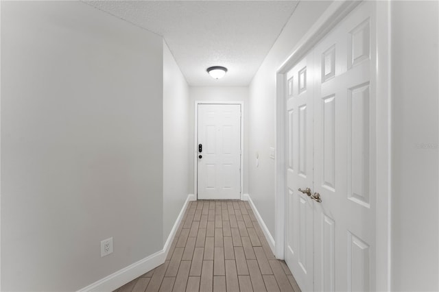 hallway with a textured ceiling and hardwood / wood-style floors