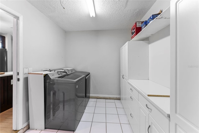 laundry room featuring cabinets, a textured ceiling, separate washer and dryer, and light tile patterned floors