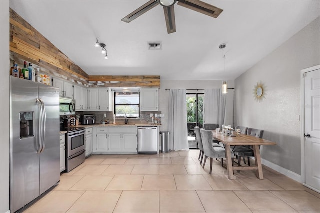 kitchen featuring light tile patterned floors, white cabinets, stainless steel appliances, track lighting, and vaulted ceiling