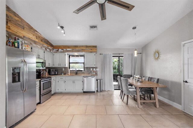 kitchen featuring lofted ceiling, sink, tasteful backsplash, decorative light fixtures, and appliances with stainless steel finishes