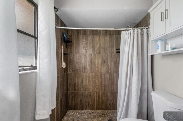 bathroom with toilet and a shower with shower curtain