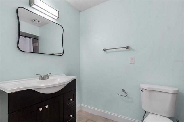 bathroom with vanity, tile patterned flooring, and toilet