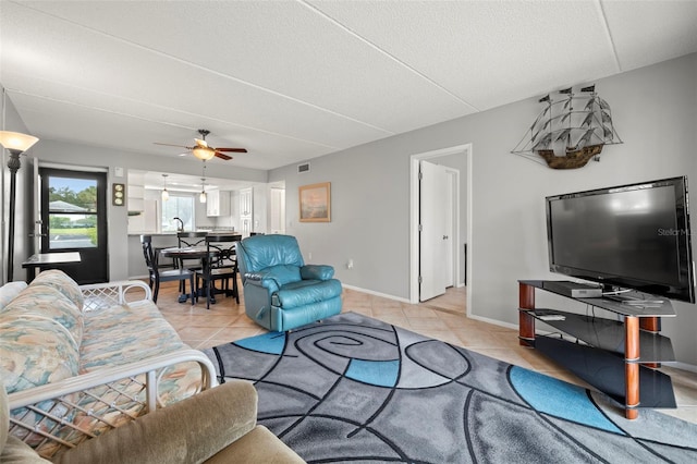 living area featuring baseboards, visible vents, ceiling fan, a textured ceiling, and light tile patterned flooring