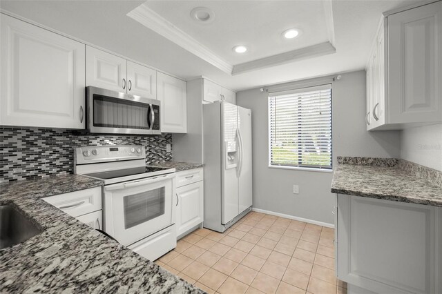 kitchen featuring white appliances, a raised ceiling, and white cabinets