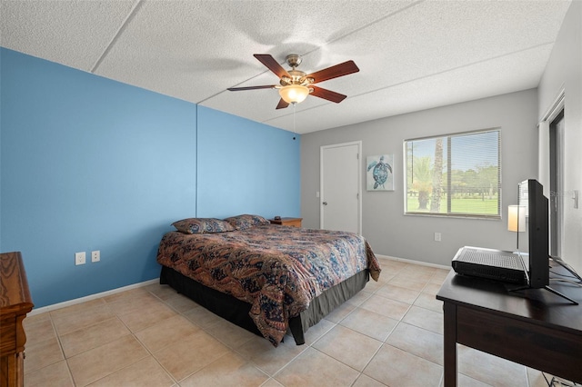 bedroom with a ceiling fan, light tile patterned flooring, a textured ceiling, and baseboards