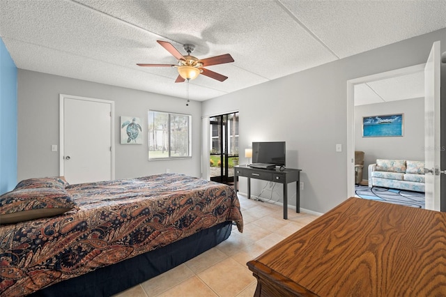 bedroom featuring light tile patterned floors, a textured ceiling, baseboards, and a ceiling fan