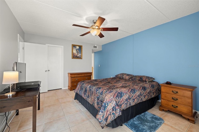 bedroom with ceiling fan, light tile patterned floors, a textured ceiling, and visible vents