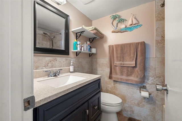 bathroom featuring toilet, a wainscoted wall, tile walls, and vanity