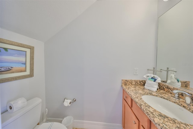 bathroom featuring toilet, vanity, and vaulted ceiling
