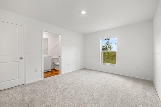 unfurnished bedroom featuring ensuite bath and carpet flooring