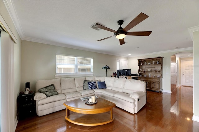 living area with crown molding, arched walkways, ceiling fan, and dark wood-style flooring